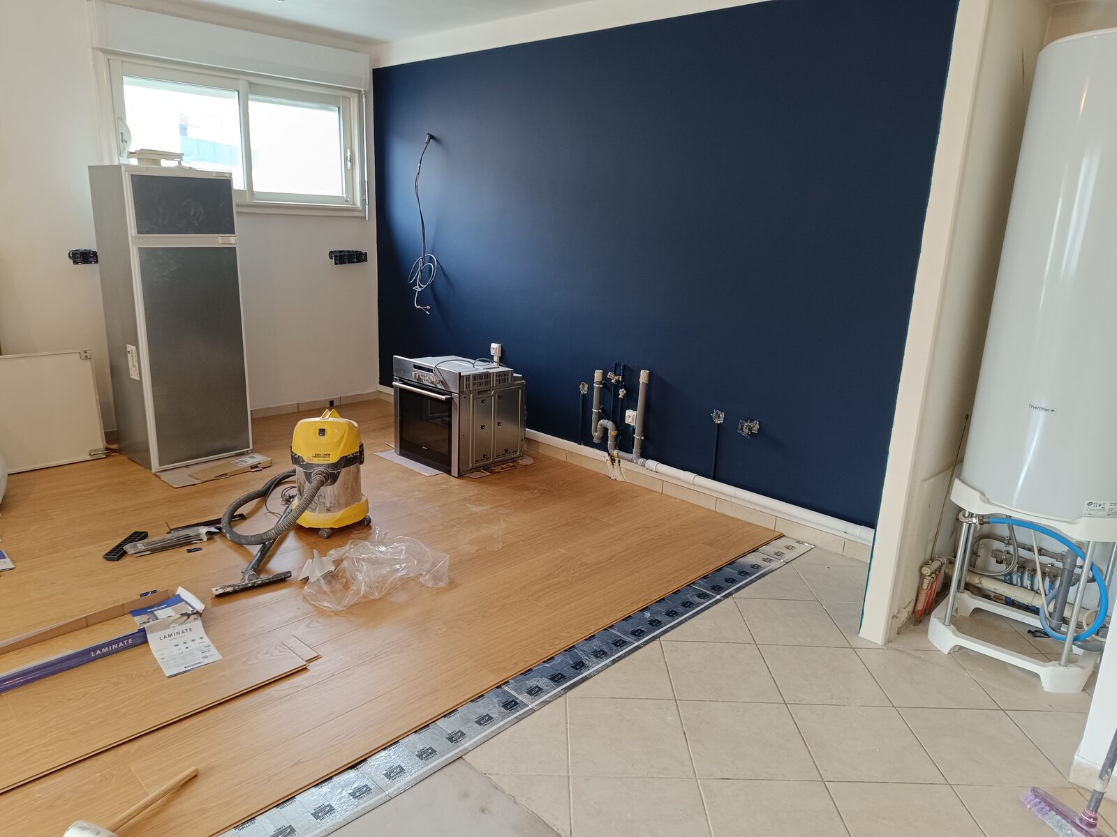 Pose de parquet flottant et peinture mur bleu navy en cours de chantier